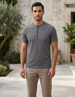 Man wearing a gray short-sleeve shirt and beige pants standing outdoors.