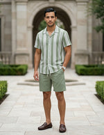 Man wearing a green and white striped shirt and shorts standing in front of a classical building.