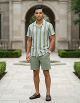 Man wearing a green and white striped shirt and shorts standing in front of a classical building.