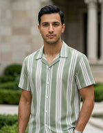 Man wearing a green and white striped shirt standing in front of a building with columns.