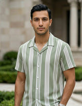 Man wearing a green and white striped shirt standing in front of a building with columns.