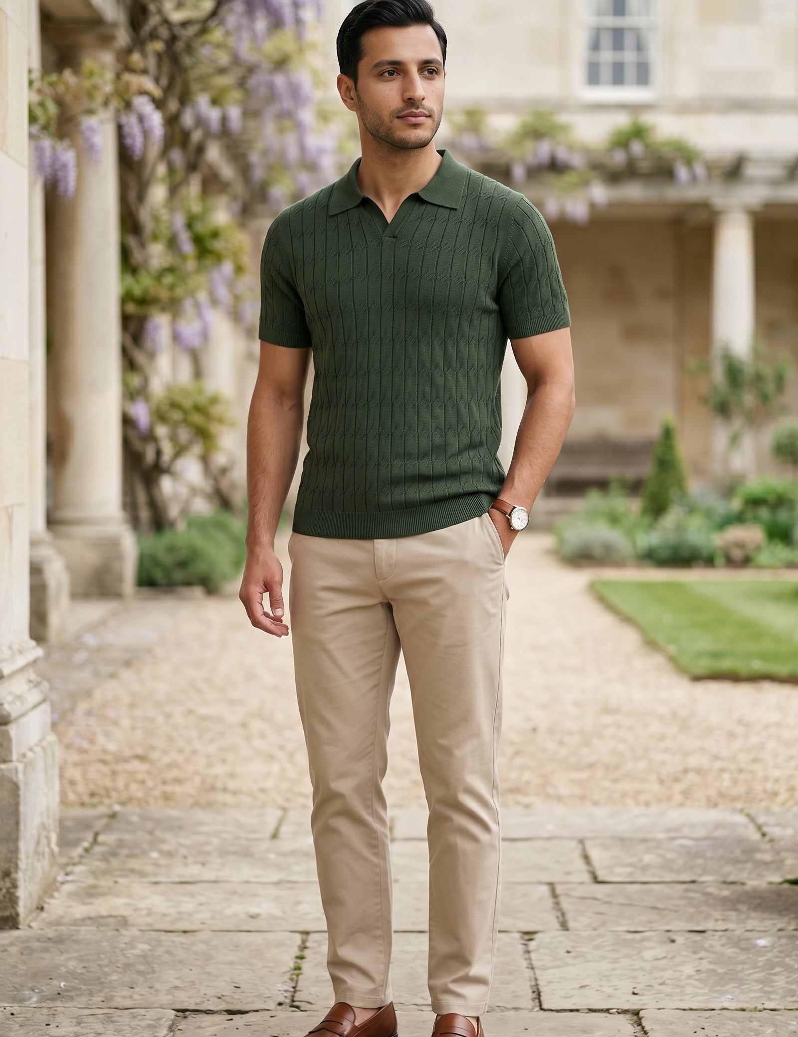 Man wearing a green polo shirt and beige pants standing in a garden setting.