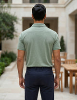 Man wearing a green polo shirt and dark pants standing in an outdoor setting.