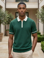 Man wearing a green polo shirt with white trim standing outdoors.