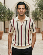 Man wearing a striped polo shirt standing outdoors with plants and a building in the background