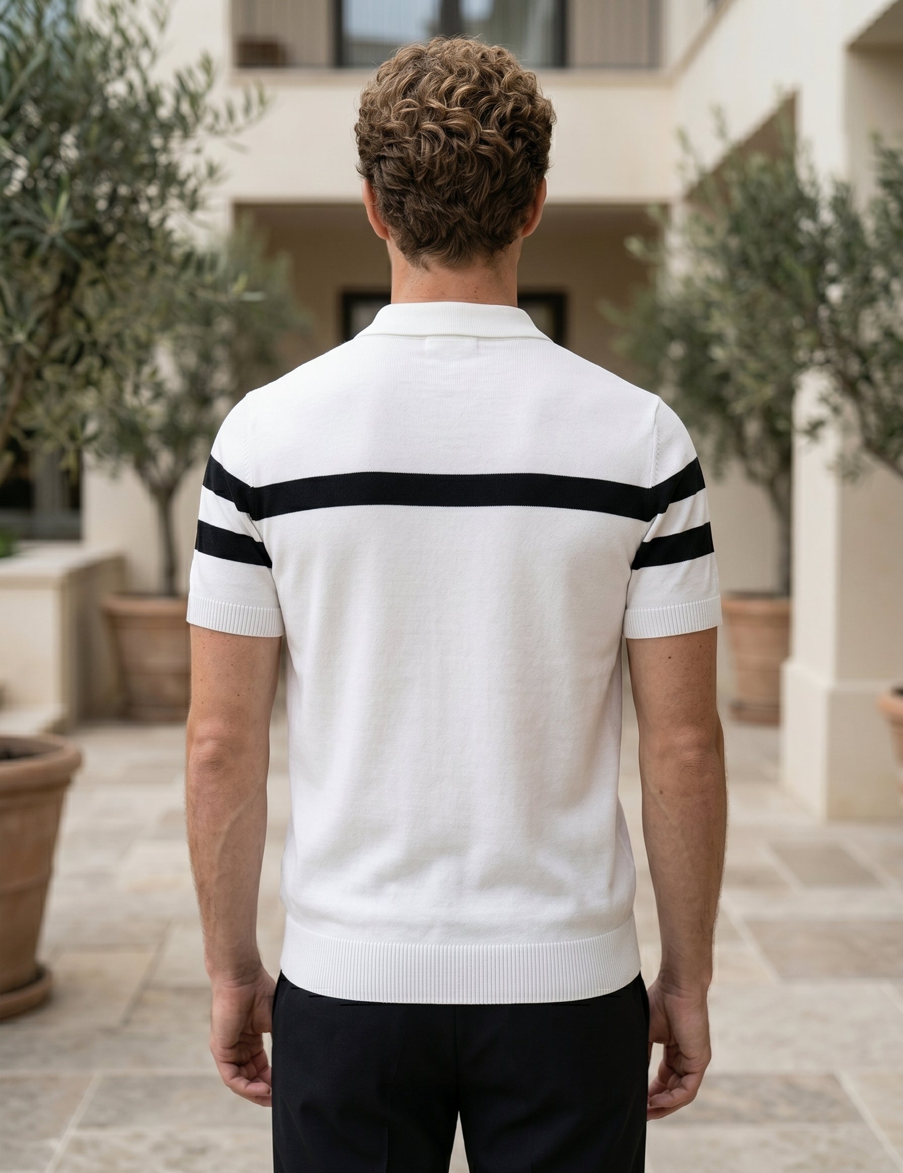 Man wearing a white polo shirt with black stripes outdoors