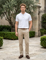 Man wearing a white polo shirt and beige pants standing outdoors on a stone path.