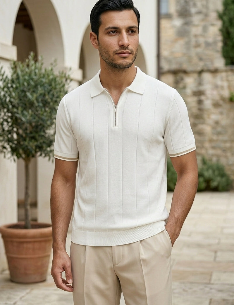Man wearing a white short-sleeve shirt and beige pants standing outdoors.