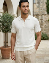 Man wearing a white short-sleeve shirt and beige pants standing outdoors.