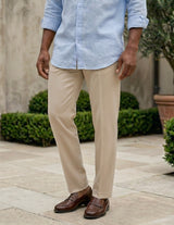 Men wearing a light blue shirt, beige pants, and brown shoes standing outdoors.