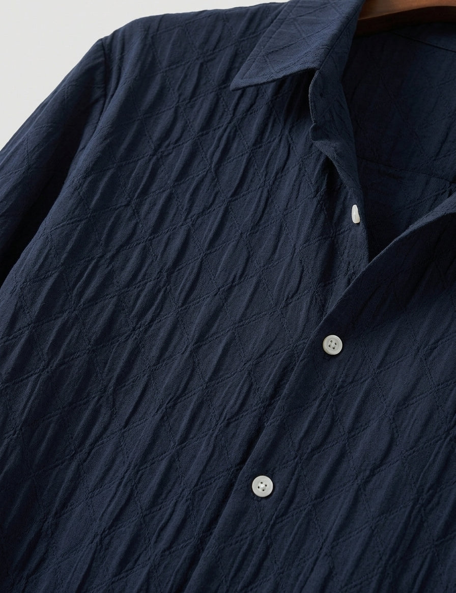Navy blue textured shirt with white buttons on a neutral background