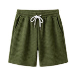 Olive green textured drawstring summer shorts with elastic waistband on a white background.