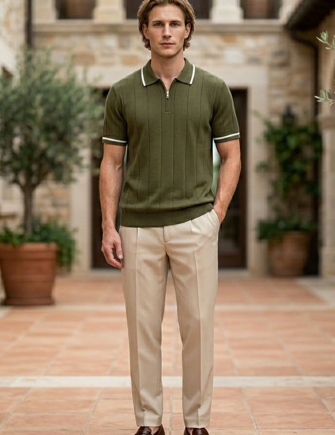 Olivo - Man wearing a green polo shirt and beige pants standing in an outdoor setting with stone walls and potted plants.