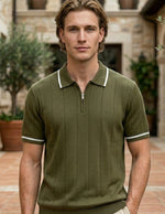 Olivo - Man wearing a green polo shirt standing in an outdoor setting with stone walls and potted plants.