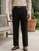 Person wearing a beige shirt, black pants, and brown shoes on a patio.