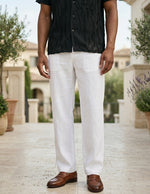 Person wearing a black shirt, white pants, and brown shoes on a blurred outdoor background
