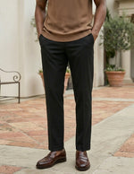 Person wearing a brown shirt, black pants, and brown shoes standing on a patio.
