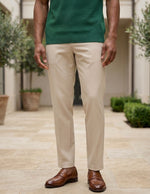 Person wearing a green shirt, beige pants, and brown shoes standing outdoors.