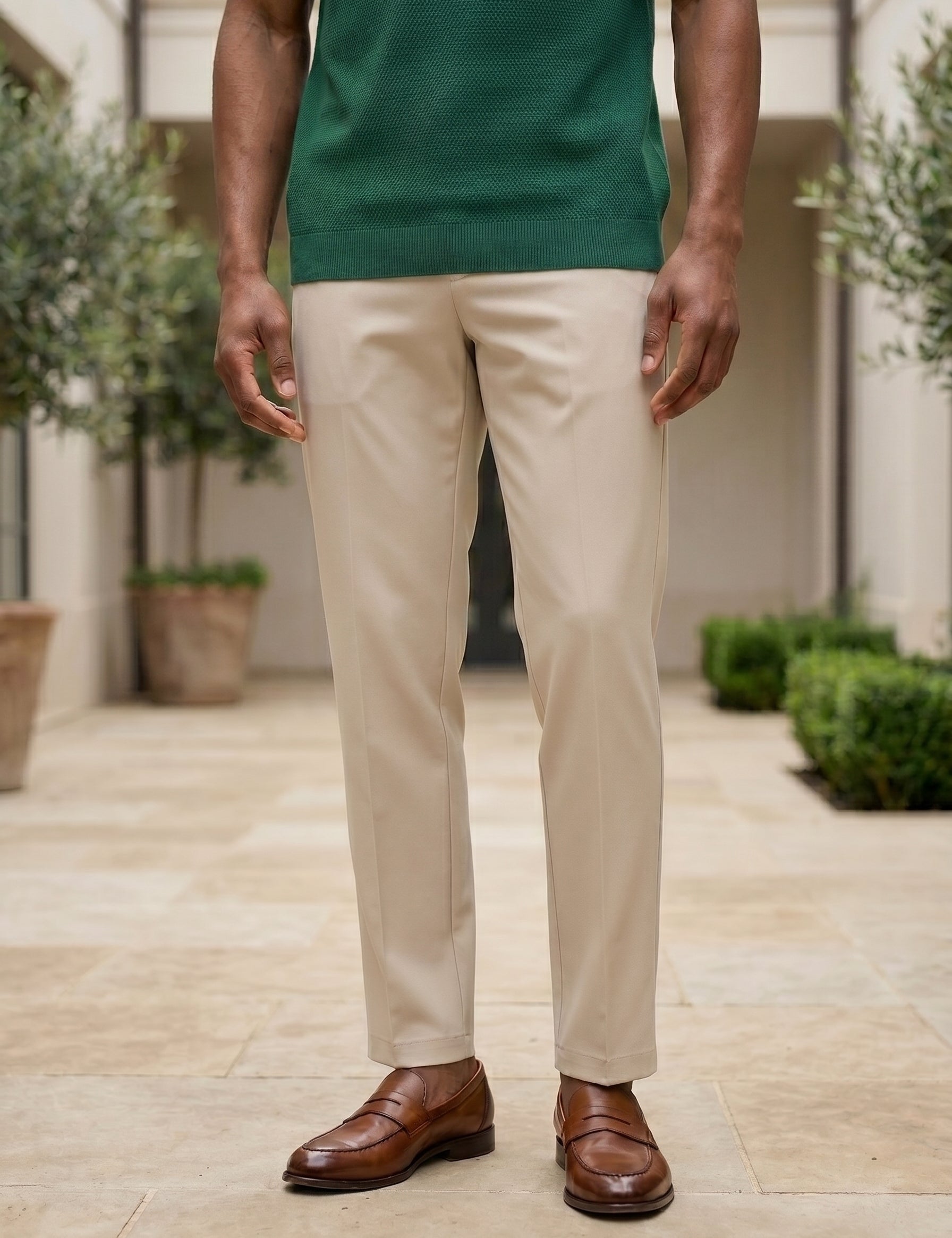 Person wearing a green shirt, beige pants, and brown shoes standing outdoors.