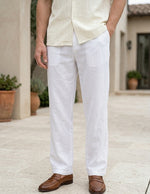 Person wearing a light-colored shirt, white pants, and brown shoes outdoors.