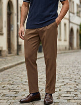 Person wearing a navy polo shirt and brown pants on a cobblestone street.