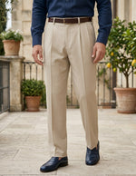 Person wearing beige dress pants with a blue shirt and dark shoes outdoors.