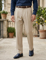 Person wearing beige dress pants with a blue shirt and dark shoes outdoors.