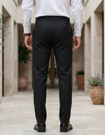 Person wearing black pants and a white shirt in an outdoor back view pant.