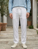 Person wearing light blue shirt and white pants standing outdoors on a wooden deck.
