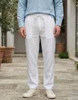 Person wearing light blue shirt and white pants standing outdoors on a wooden deck.