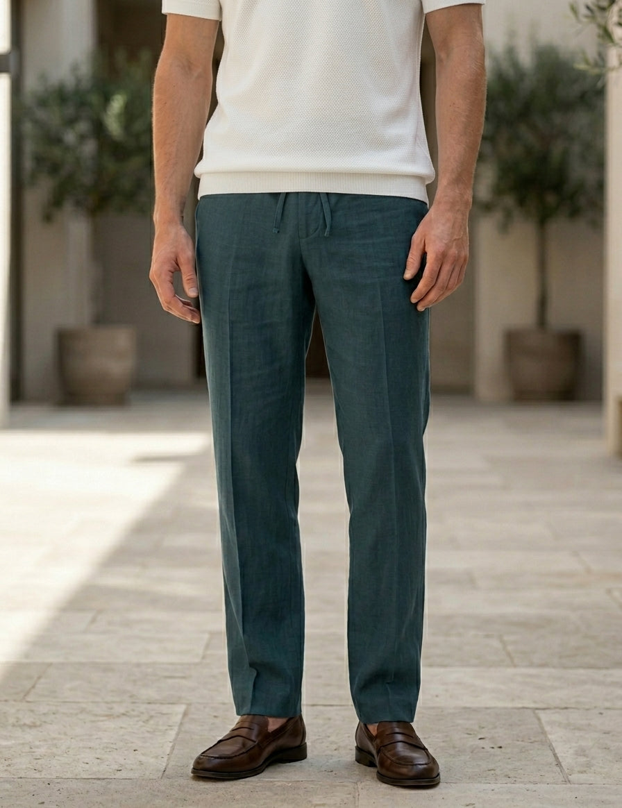 Person wearing teal pants and a white shirt standing on a wooden floor.