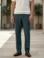 Person wearing teal pants and a white shirt standing on a wooden floor.