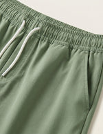 Green shorts with a white drawstring on a light background