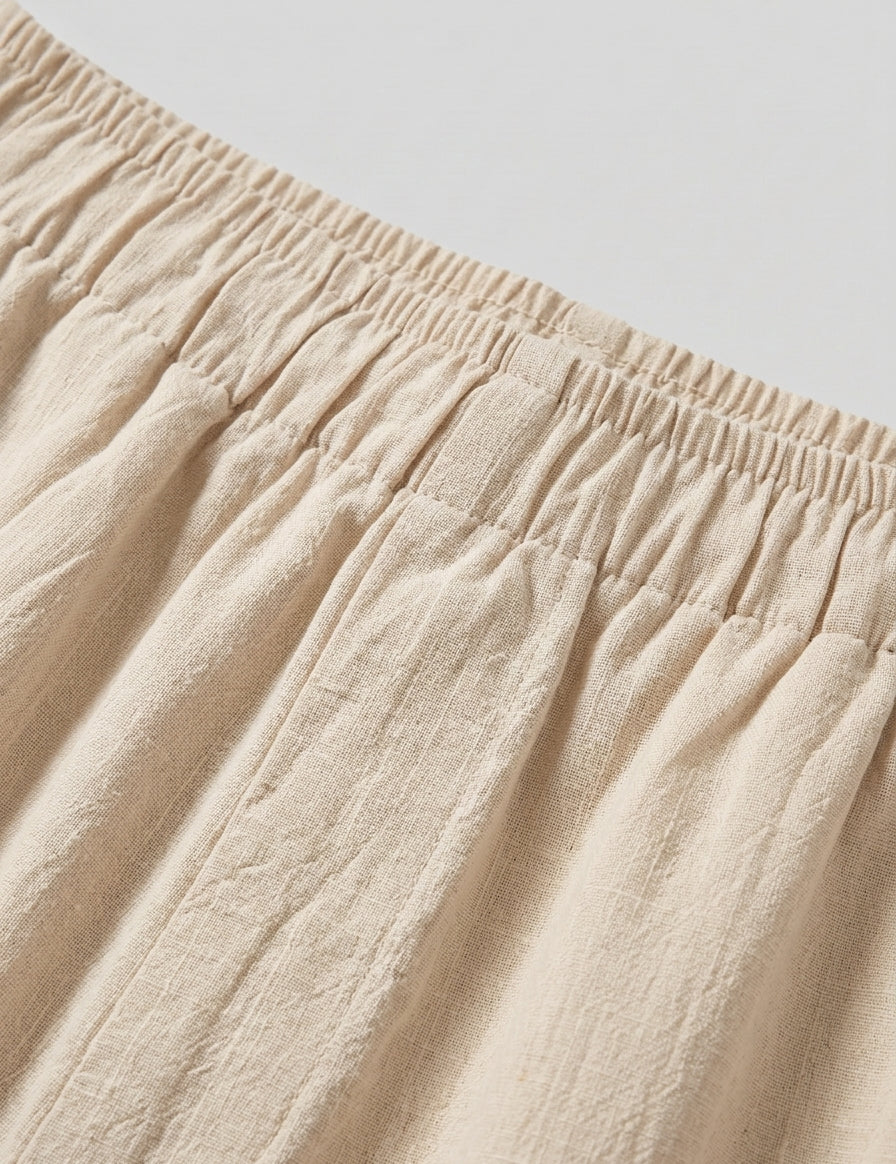 Close-up of beige fabric with an elastic waistband on a light gray background