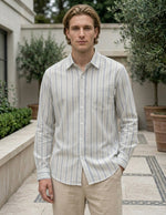 Man wearing a striped shirt and beige pants standing outdoors.