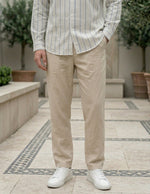 Person wearing a striped shirt and beige pants with white sneakers in an outdoor setting.