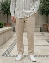 Person wearing a striped shirt and beige pants with white sneakers in an outdoor setting.