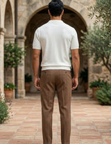 Rosato - Man walking away from the camera in a stone archway with plants and a building in the background