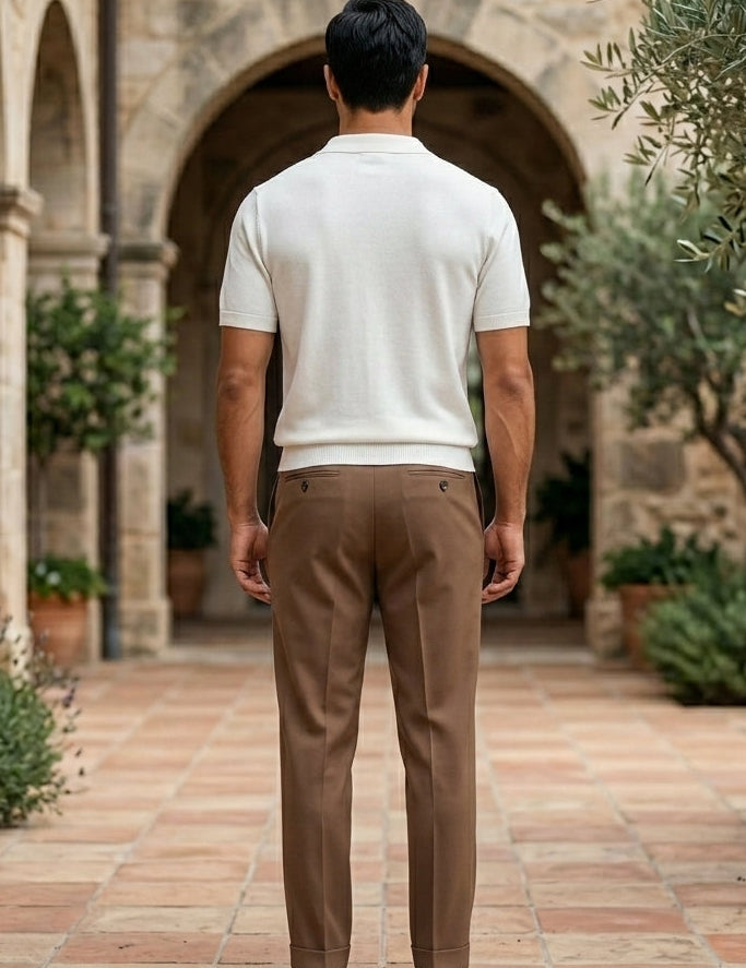 Rosato - Man walking away from the camera in a stone archway with plants and a building in the background