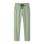 Sage green jogger pants with elastic waistband and tapered legs on a white background.