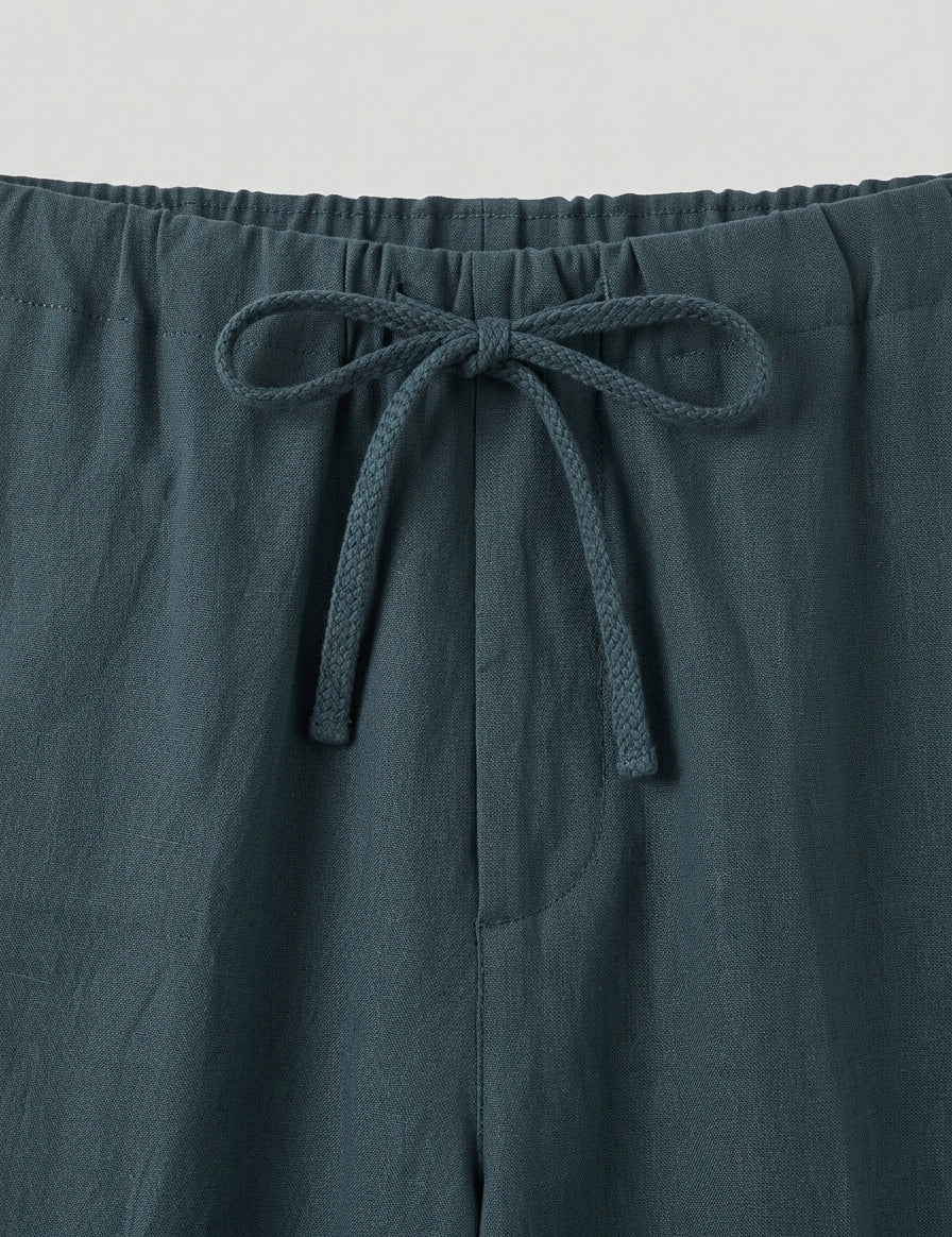 Teal pants with a drawstring waist on a light gray background