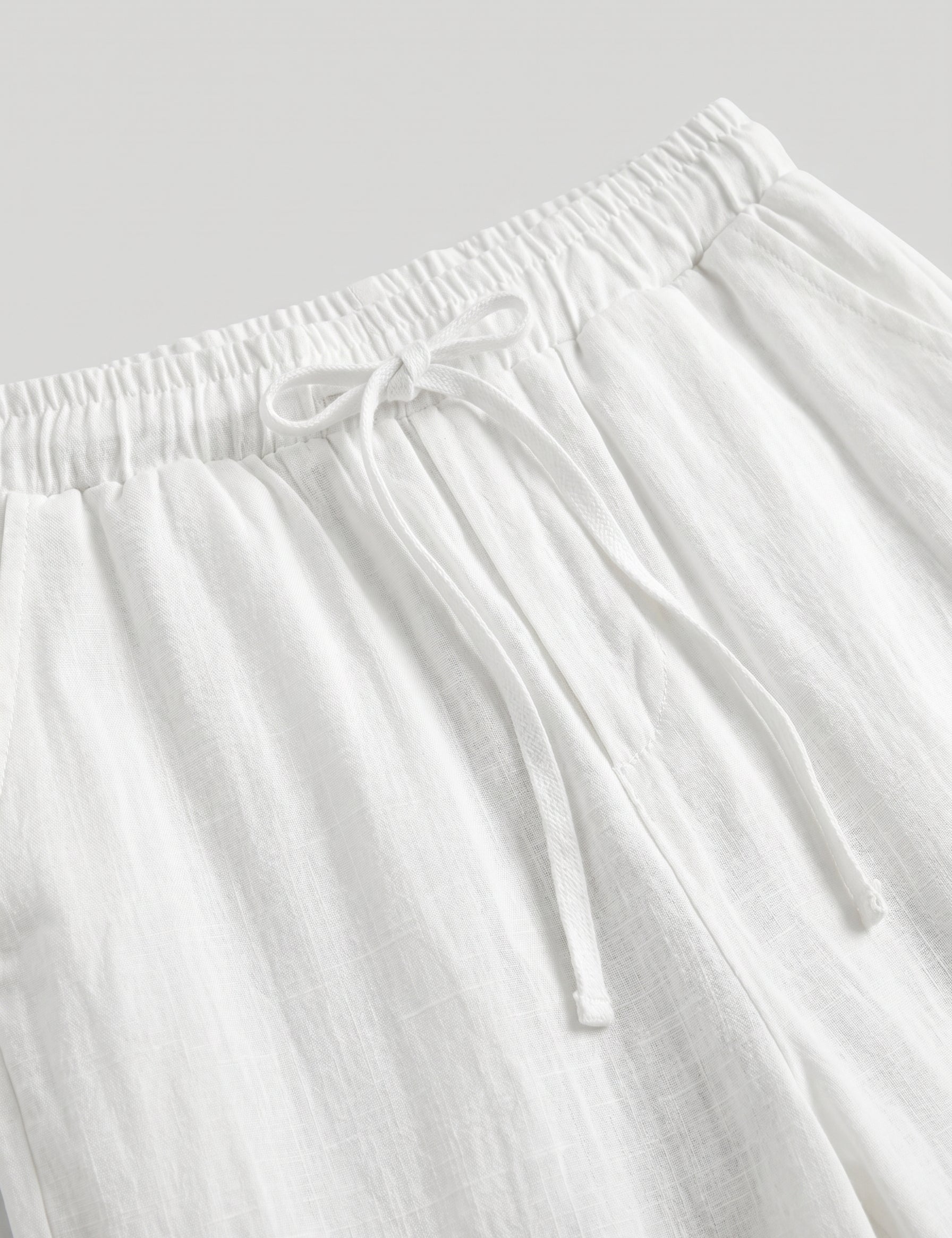 White pants with drawstring waist on a light gray background