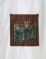 White shirt with a patch featuring brown stripes and green fabric on a white background