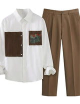 White shirt with brown patchwork design and brown pants on a light gray background