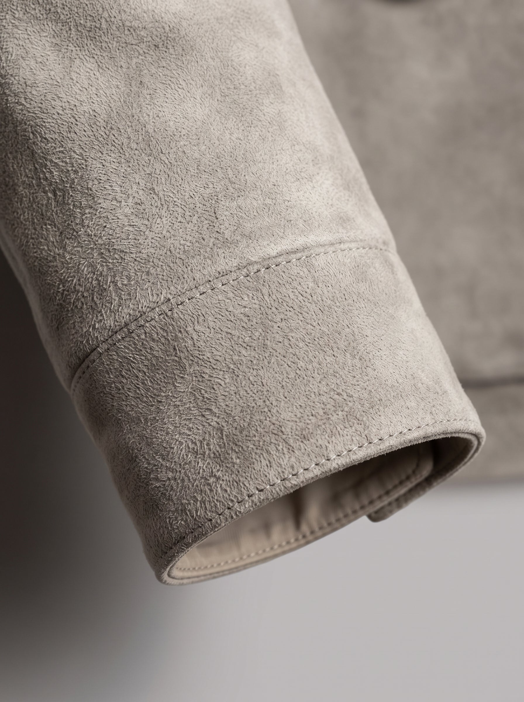 Close-up detail of a light gray suede or nubuck sleeve cuff, showing the soft textured fabric and clean stitching.