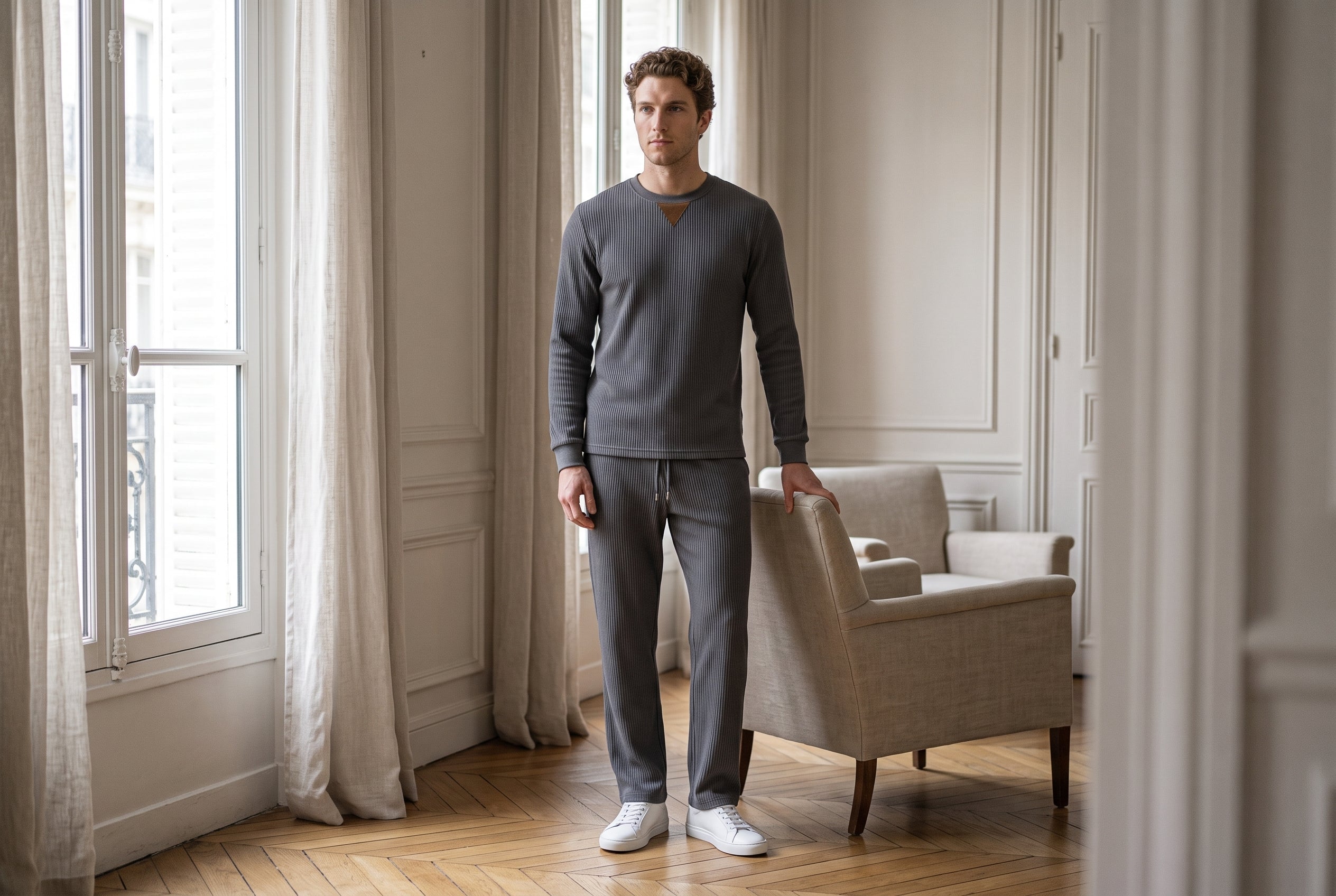 Man in a charcoal ribbed-knit crewneck and straight-leg pant set in a bright Paris apartment