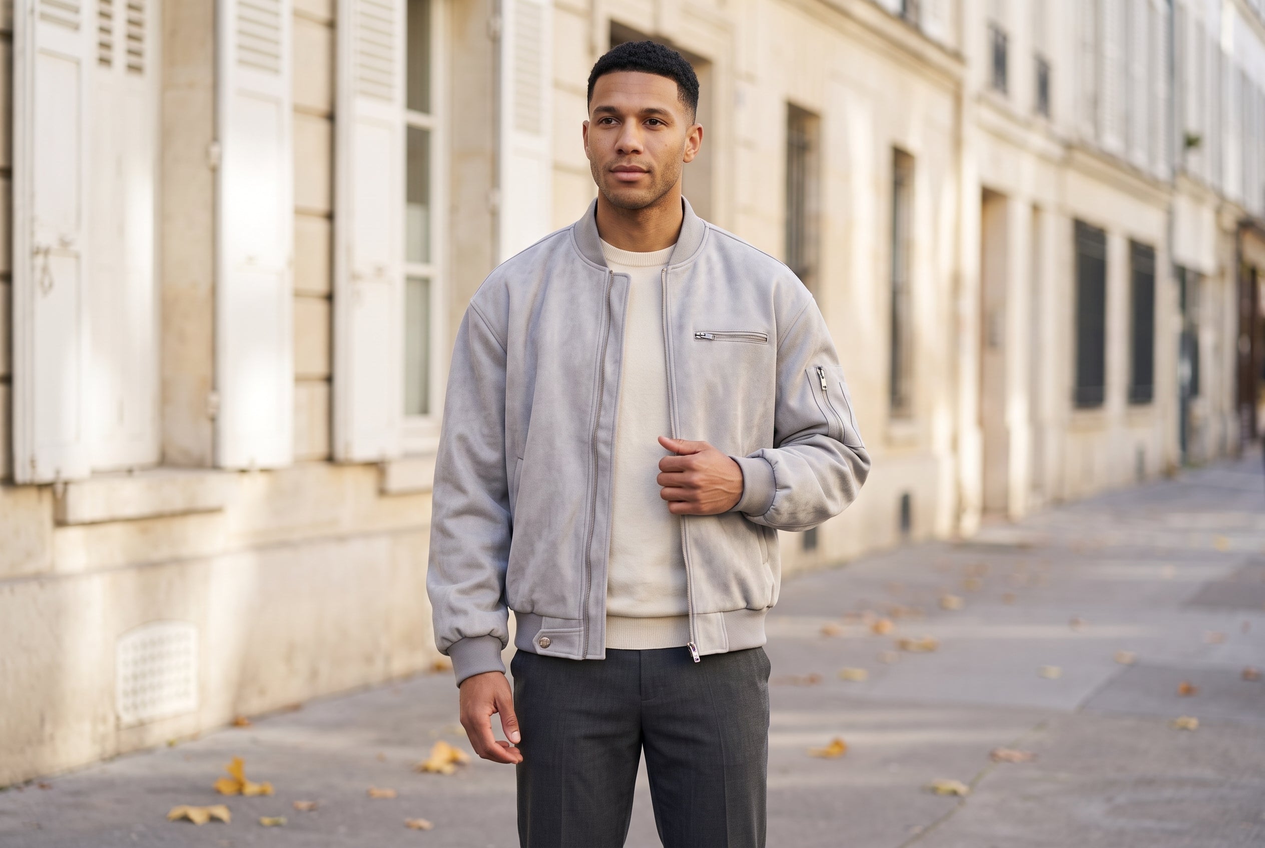 Man in a light grey washed faux suede MA-1 bomber jacket on a sunlit Paris street in autumn