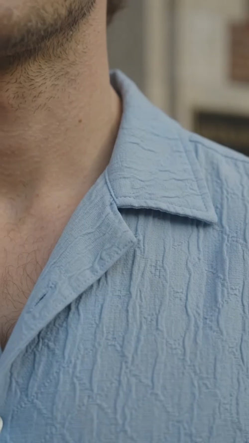 Model wearing a light blue shirt in a video